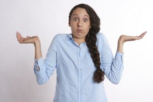 Young woman in a blue shirt with her palms facing upward looking confused